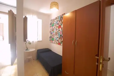 a small room with a blue bed and a window at Appartamento Bouganville in Castellammare del Golfo