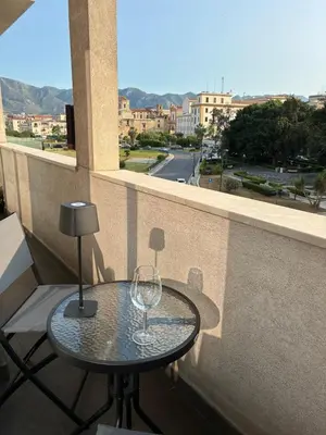 a table on a balcony with a wine glass at D & C Apartment in Palermo
