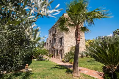 an old stone building with a palm tree in the foreground at Villa Cannamele in Carini