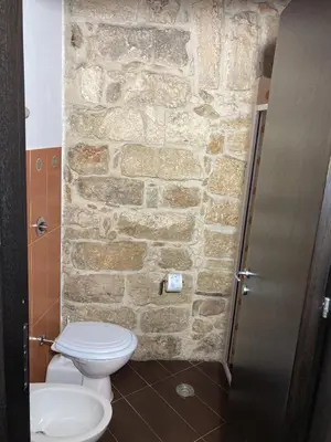 a bathroom with a toilet and a stone wall at Casa Vacanza 