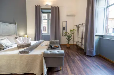 a bedroom with a large bed and a chair at Le suite di Alba in Palermo
