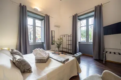 a bedroom with a bed and two large windows at Le suite di Alba in Palermo