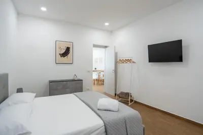 a white bedroom with a bed and a flat screen tv at Home1995 in Palermo