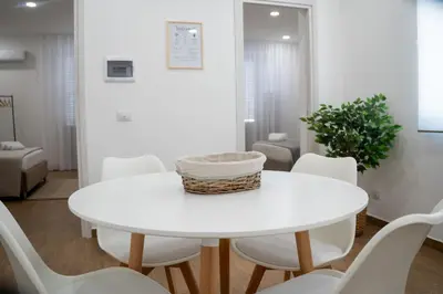 a white dining room with a white table and white chairs at Home1995 in Palermo