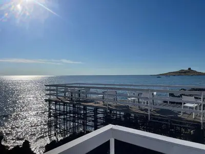 a view of a pier with chairs and the ocean at la vue sur la mer in Capaci