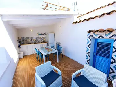 a room with a table and chairs and a kitchen at Casa Sciàpó in Terrasini