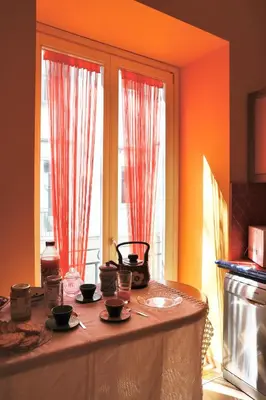 a table in a kitchen with two windows with red curtains at Maria's apartment alla Magione, appartamento in centro in Palermo