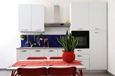 a kitchen with white cabinets and a table with a potted plant at Appartamenti Marì 1 in Palermo