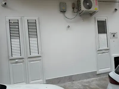 a white wall with two doors and a fan at Donna Franca in Cinisi