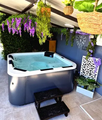 a hot tub in a garden with purple flowers at Chalet Ponte Paradiso Suite & SPA in Santa Cristina Gela