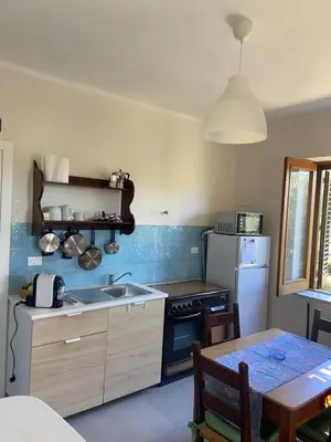 a kitchen with a sink and a refrigerator and a table at I Carrubi in Lascari