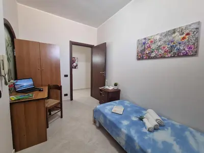 a bedroom with a bed and a desk with a laptop at House Calamigna in Ventimiglia di Sicilia