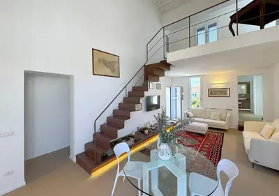 a living room with a staircase and a table and chairs at Solemar Sicilia - Villa Regina Elena in Palermo