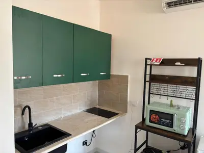 a kitchen with green cabinets and a sink and a microwave at cielo blu in San Vito lo Capo