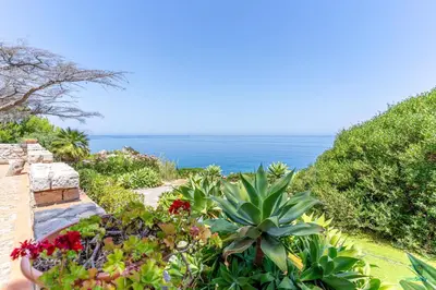 a garden with flowers and the ocean in the background at Verosicily Villa Aspra in Bagheria
