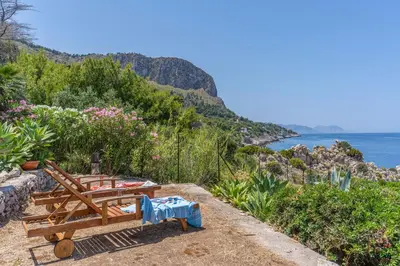a bench sitting on a hill next to the ocean at Verosicily Villa Aspra in Bagheria