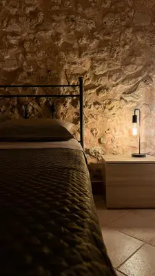 a bedroom with a bed and a stone wall at Appartamento Cinisi in Cinisi