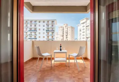 a table with chairs and a bottle of wine on a balcony at Guest House Conca D'oro in Palermo