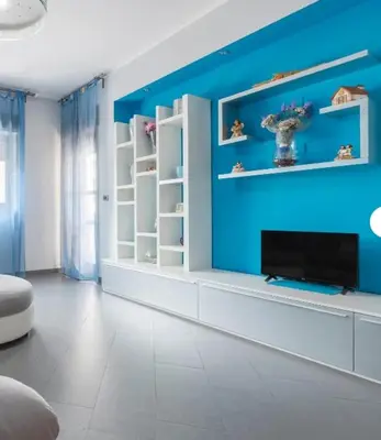 a room with a blue wall with shelves and a tv at Guest House Conca D'oro in Palermo