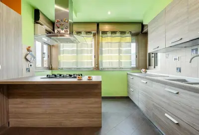 a kitchen with wooden cabinets and green walls at Guest House Conca D'oro in Palermo
