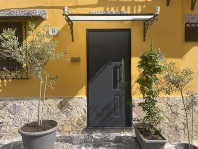 a black door on a yellow house with two plants at La Stanza del Viaggiatore in Palermo