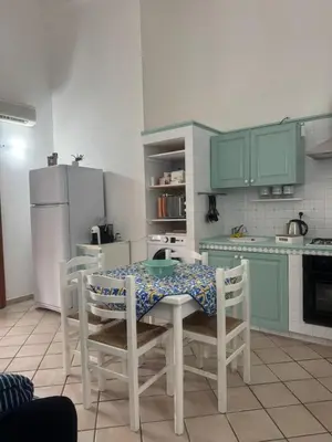 a kitchen with a table and chairs and a refrigerator at Lulu' Home - Guidaloca - Scopello in Scopello