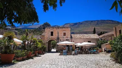 an old building with tables and umbrellas in a courtyard at Lulu' Home - Guidaloca - Scopello in Scopello