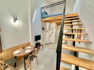a dining room with a table and a staircase at Loft Pergola, posizione strategica in Castellammare del Golfo