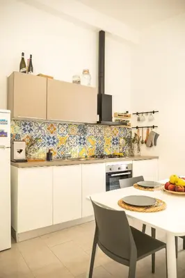 a kitchen with white cabinets and a table with chairs at La suite al Teatro Massimo in Palermo