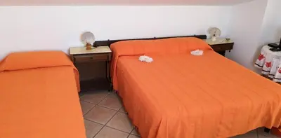 a bedroom with two beds with orange sheets and two night stands at Casa a Campofelice di Roccella in Campofelice di Roccella