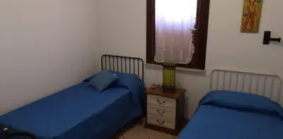 two beds in a bedroom with blue sheets and a window at Casa a Campofelice di Roccella in Campofelice di Roccella