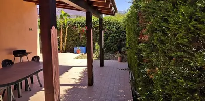 a patio with a table and a bench next to a hedge at Casa a Campofelice di Roccella in Campofelice di Roccella