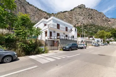 a white house on a street with a mountain at GuestHost - Seaview Apartments near Palermo in Palermo