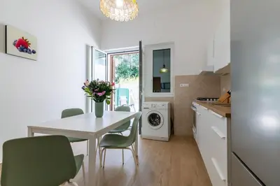 a kitchen with a white table and green chairs at GuestHost - Seaview Apartments near Palermo in Palermo