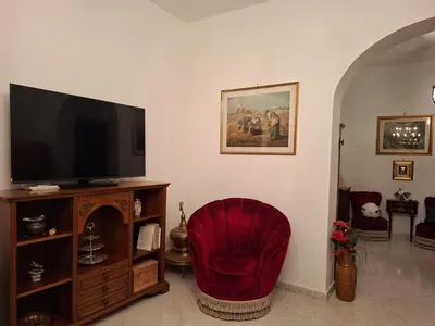 a living room with a tv and a red chair at Casa Mirella in Aspra