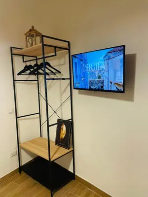 a room with a tv and a shelf with shoes at Casa di Anna in Palermo