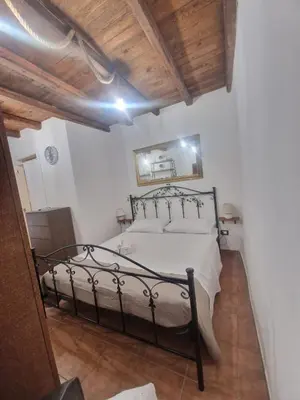a bedroom with a bed with white sheets and a wooden ceiling at Al vicolo holiday home in Palermo