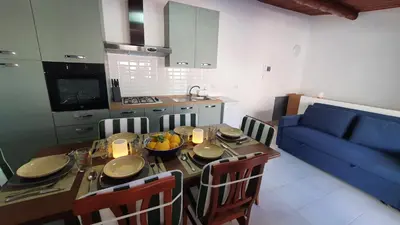 a kitchen and a dining room table with a blue couch at Casa Nonna Rosa in Balestrate