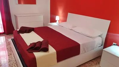 a bedroom with a large bed with red walls at Casa Nonna Rosa in Balestrate
