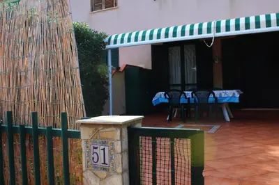 a house with a green fence and a table and chairs at Summer House in Buonfornello