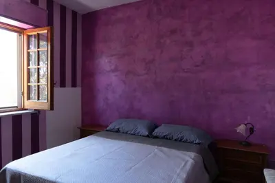 a purple bedroom with a bed and a window at Appartamento vicino Palermo - 2 bedr in Trabia in Trabia