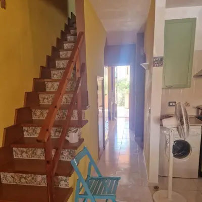 a staircase in a house with a blue chair in a hallway at Silville in Campofelice di Roccella