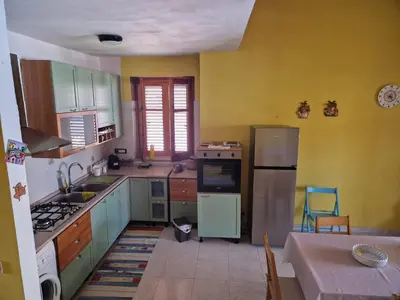 a kitchen with green and yellow cabinets and a table at Silville in Campofelice di Roccella