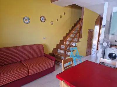 a living room with a red couch and a staircase at Silville in Campofelice di Roccella