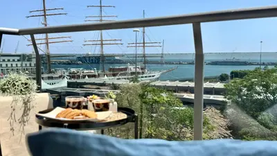 a table with a plate of food on a balcony with a boat at Castellammare Residence in Palermo