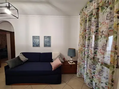 a living room with a blue couch and a window at Casa Marina in Buonfornello