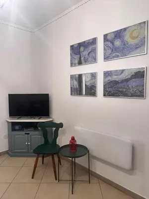 a room with a tv and a table and some paintings at Casa Marina in Buonfornello