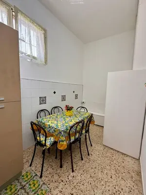 a kitchen with a table with chairs and a refrigerator at Piccolo Brasile Home in Capaci