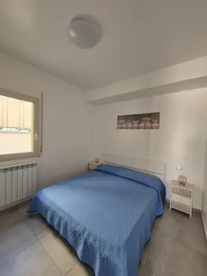 a bedroom with a blue bed and a window at ammare da mari in Castellammare del Golfo