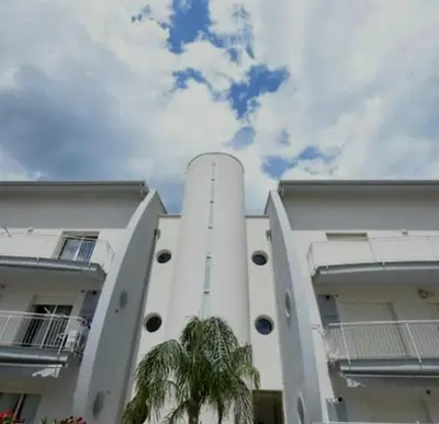 a white building with a palm tree in front of it at ammare da mari in Castellammare del Golfo